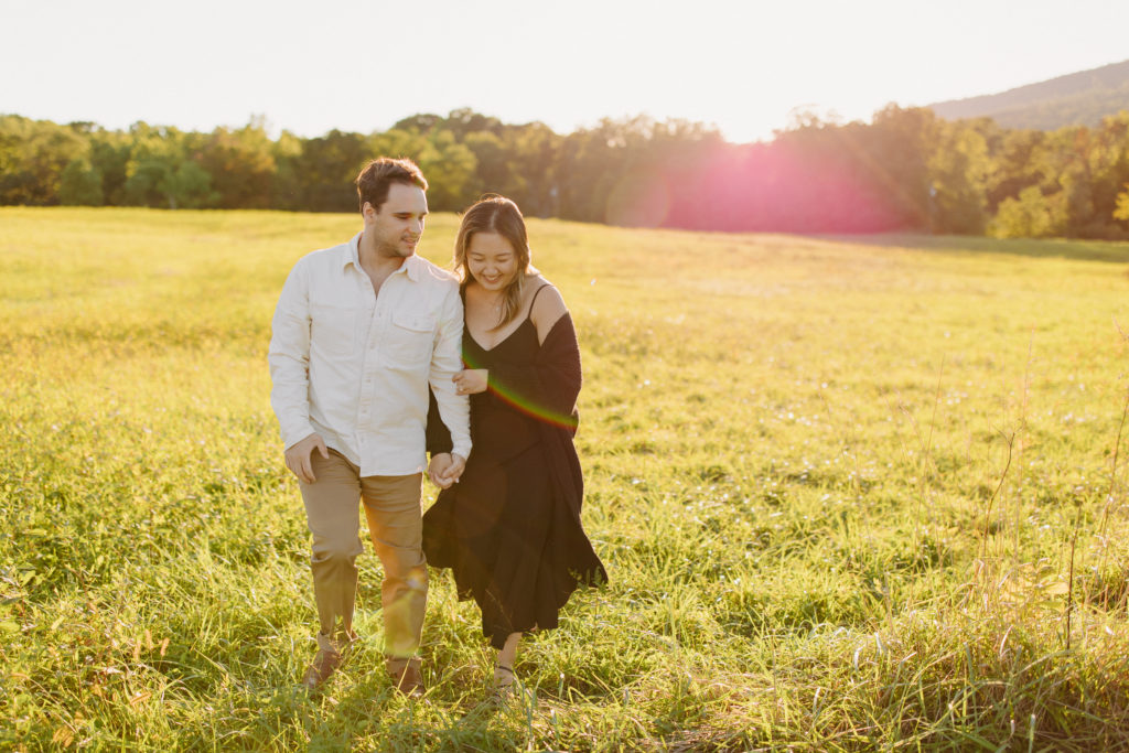 Couple walking towards the camera in a big open field during golden hour