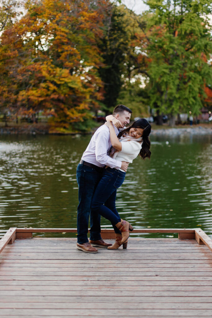 A couple about to kiss as they stand on the end of a dock. 
