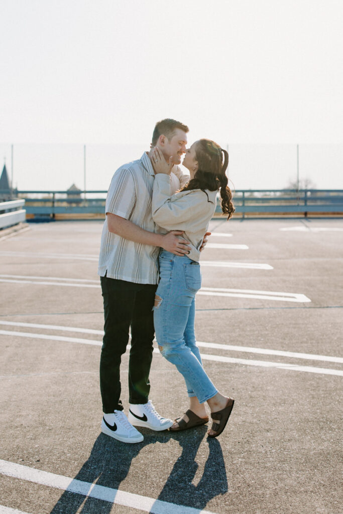A couple about to kiss as they stand on the top floor of a parking garage. 