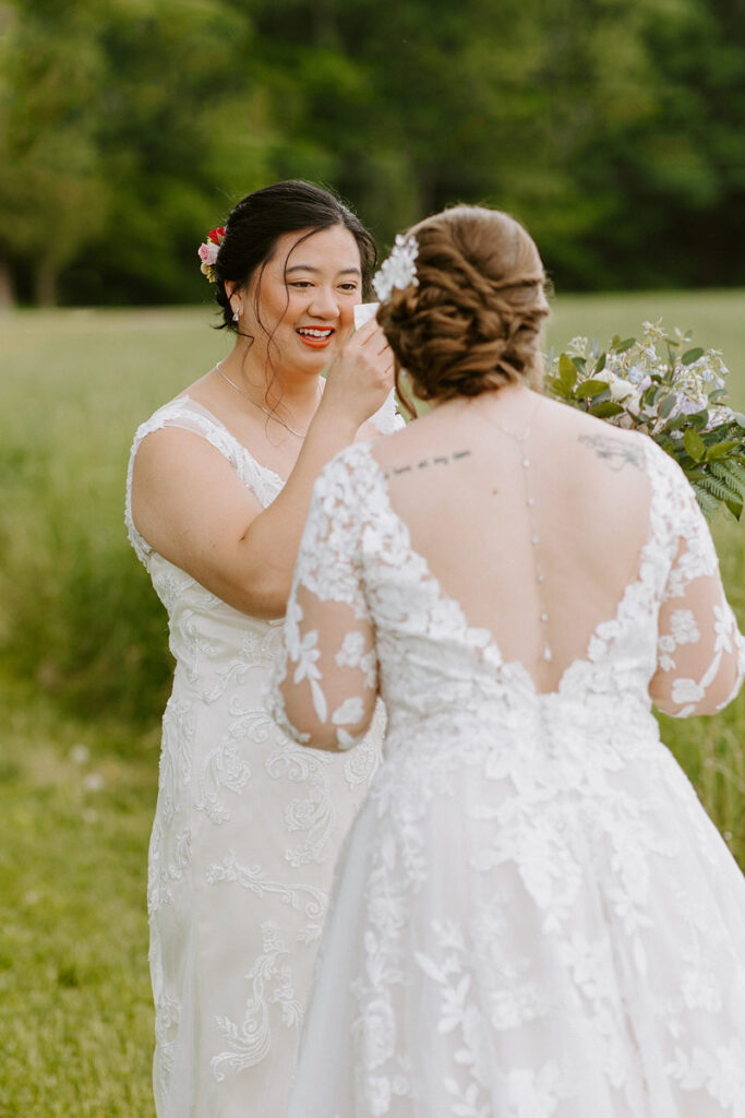 Two brides smiling at each other during their first look. 