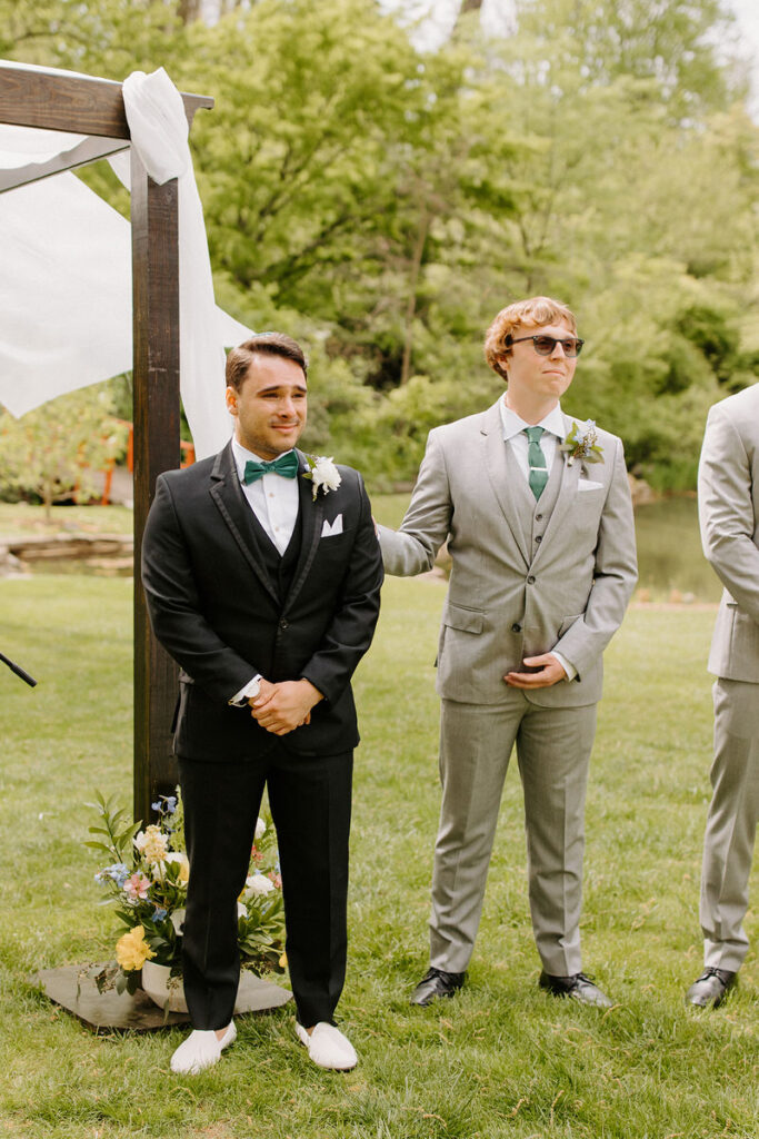 A groom standing up at the alter with his groomsmen. 