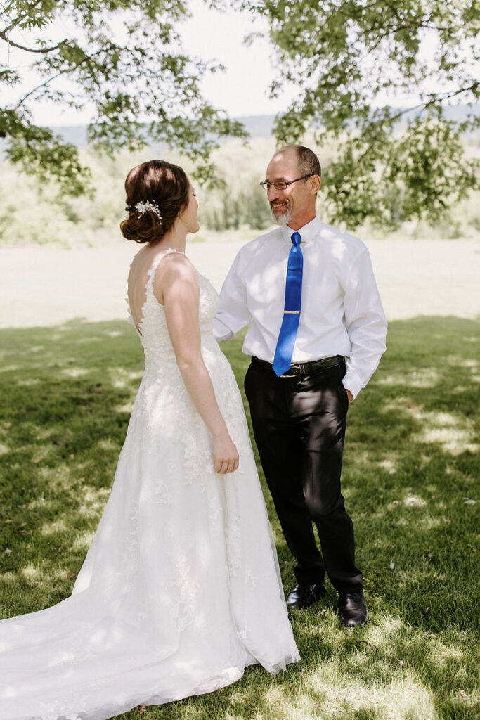 A dad smiling at his daughter in her wedding dress. 