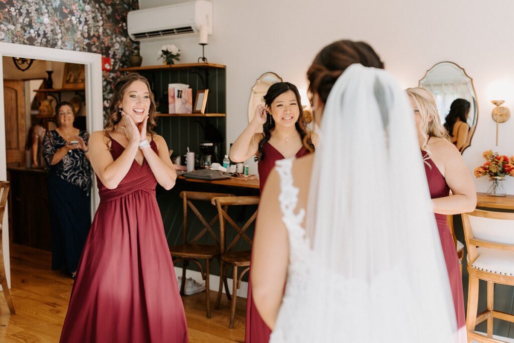 Bridesmaids smiling at a bride during a first look. 