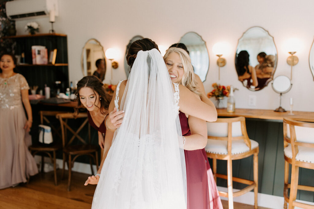 Bridesmaids hugging a bride during a first look. 