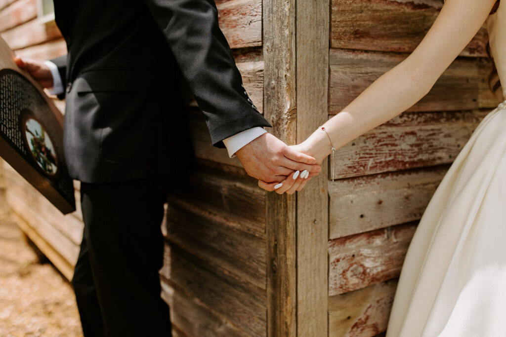 A close up views of two people reaching around a corner to hold hands. 