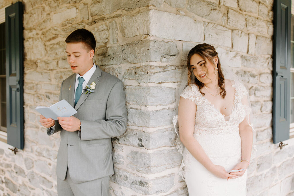 A bride and groom standing around the corner from each other while reading notes. 
