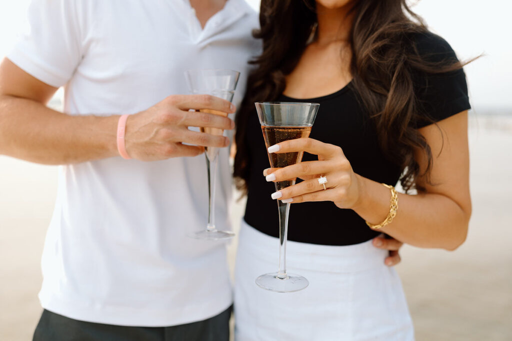A close up view of two people holding champagne glasses. 