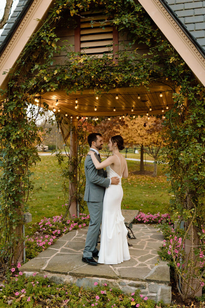 A wedding couple dancing in a small vine covered gazebo. 