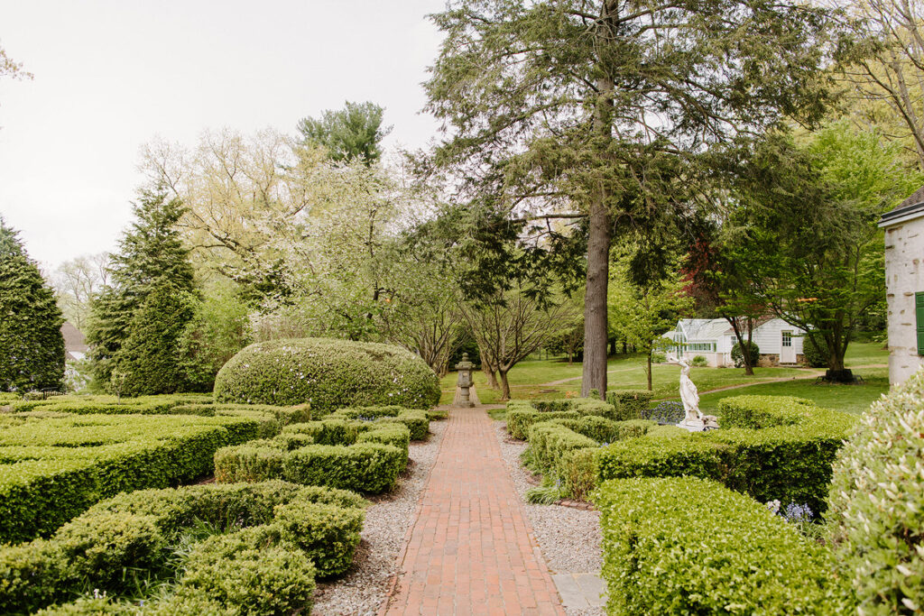 A small brick path leading through a green garden area. 