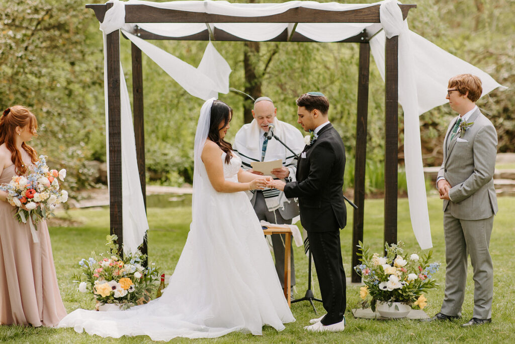A bride and groom holding hands and saying their vows at their wedding. 