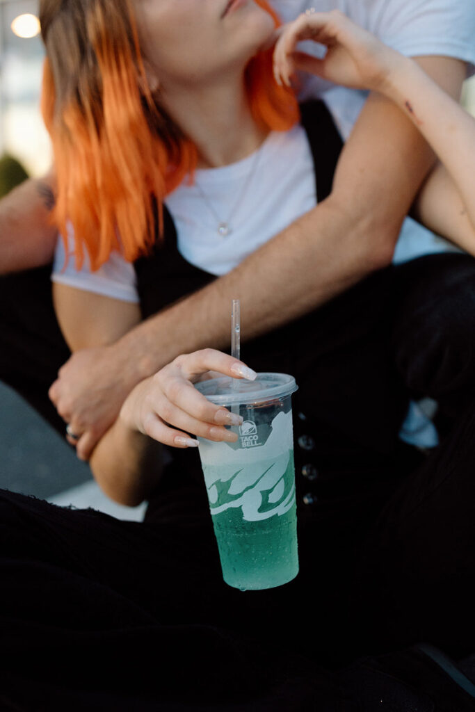 A close up view of a woman holding a baja blast with her partner's arm around her. 