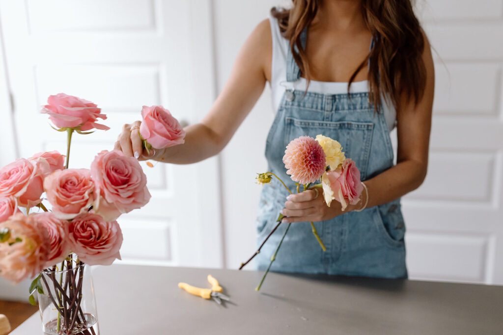 A florist placing flowers in to a vase. 