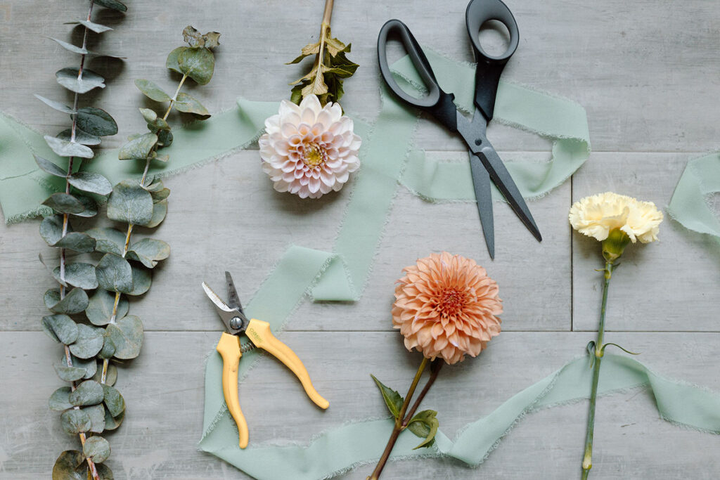 Scissors, pliers, and flowers laid out on a table. 
