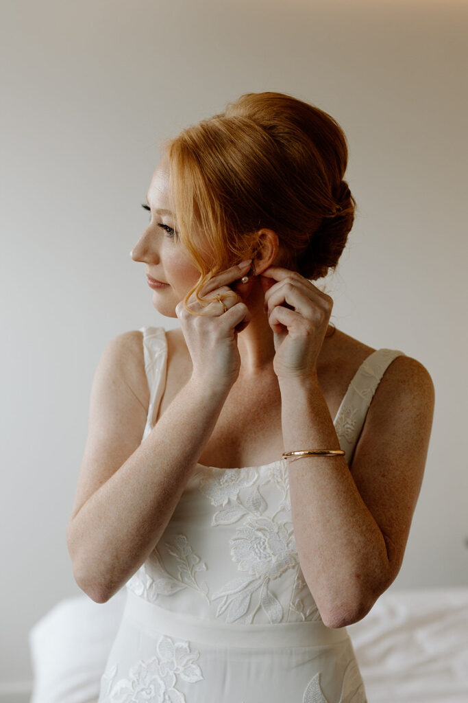 A person putting earrings on as they get ready for their wedding. 