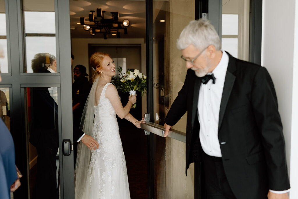 An older wedding guest holding the door open for a soon to be wed. 