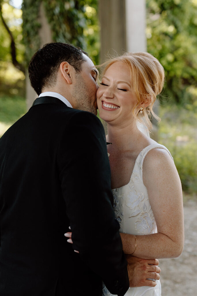 A person kissing their partner's cheek during their wedding. 
