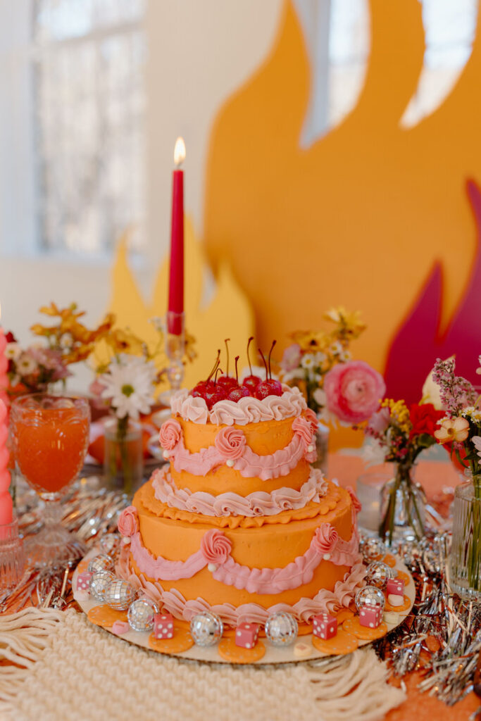 An orange and pink cake on a table.