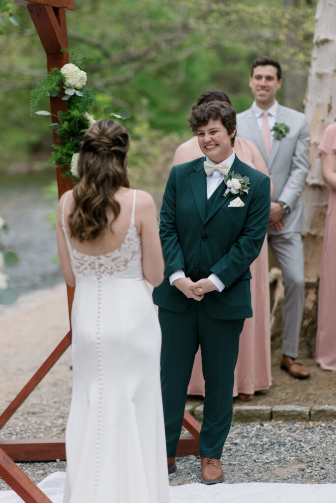 Two to-be-weds stand up at the altar smiling.