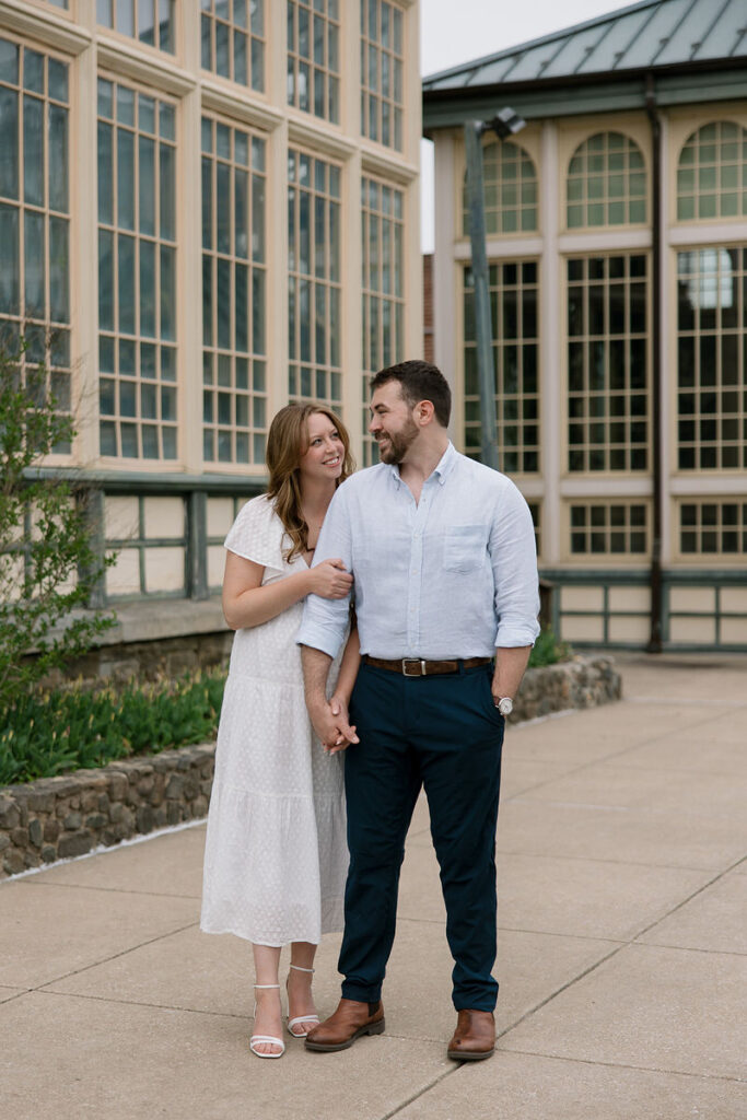 A couple holding hands and smiling while standing outside 