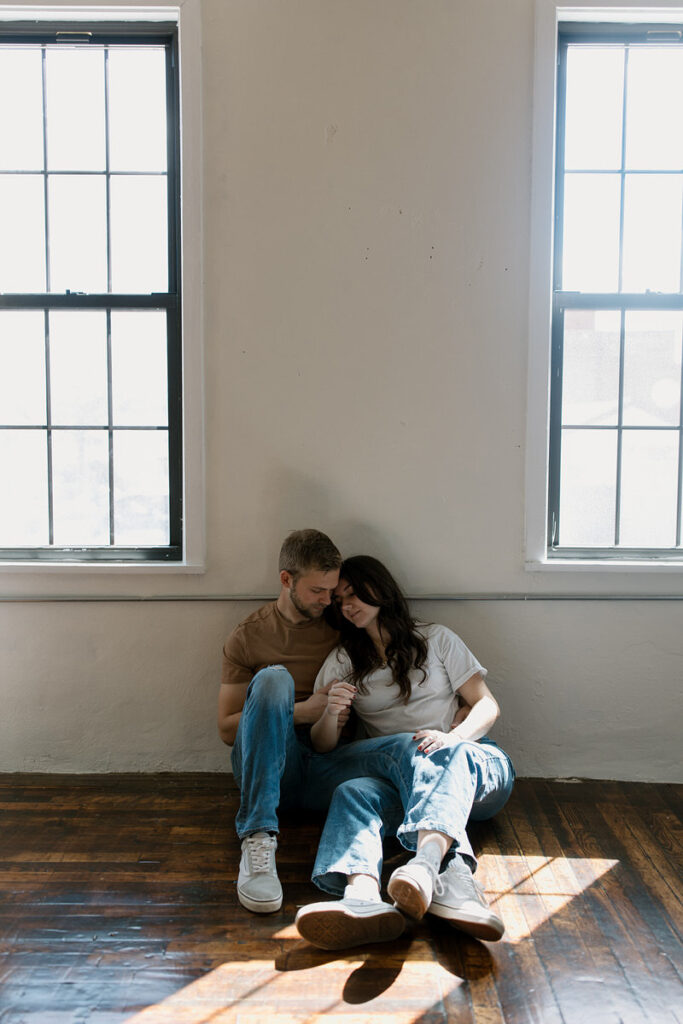 A couple sitting on the floor together with their legs over each other. 